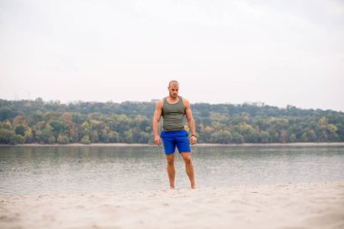 Genç erkek sporcu kumda atlamaya hazırlanıyor..