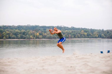 Nehir kıyısında atlayan kaslı sporcu.