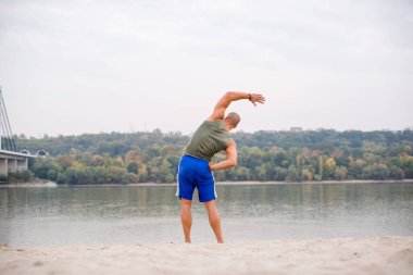 Sahilde egzersiz yapan genç bir sporcunun arka görüntüsü..
