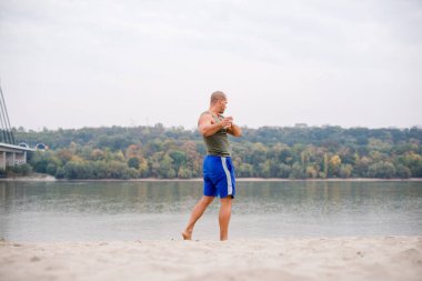 Genç sporcuların kumun üzerinde durarak esnediği alçak açılı manzara..