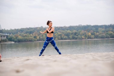 Kollarını uzatan, kumların üzerinde duran bir kadın..