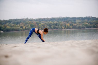 Kum üzerinde egzersiz yapan güzel bir kadın..