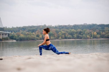 Kumsalda egzersiz yapan kadın, yan görüş.