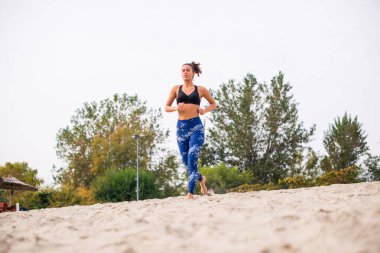 Genç bir kadın güzel bir yaz gününde kumsalda koşuyor..