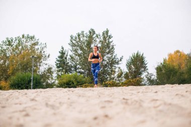 Kumda koşan güzel bir kadın, güzel görünmek için pratik yapıyor..