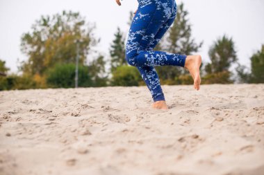 Sahilde koşan bayan sporcu, düşük kesim, yakın çekim..