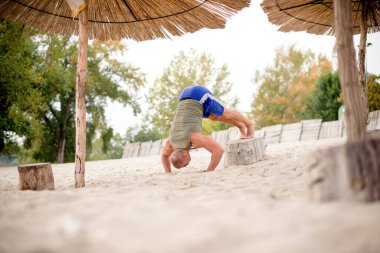 Kafkas sporcusu amuda kalkıyor, plajda egzersiz yapıyor..