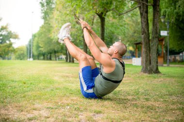 Genç sporcu halka açık parkta egzersiz yapıyor, mekik çekiyor..