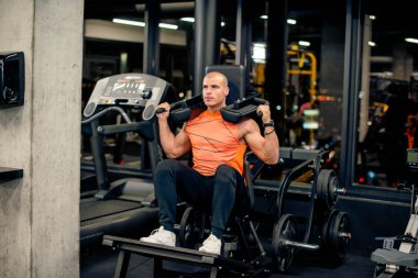 Çekici genç adam spor salonunda egzersiz yapıyor.