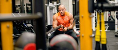 Adam spor salonunda egzersiz yapıyor, halatı çekiyor.