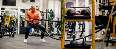 Spor salonunda adam ipi çekiyor, sıkı egzersiz.