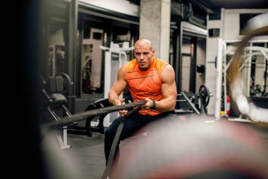 Spor salonunda adam ipi çekiyor, sıkı egzersiz.