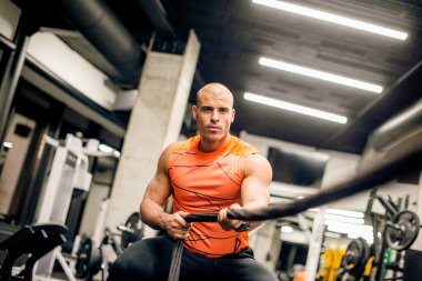 Spor salonunda adam ipi çekiyor, sıkı egzersiz.