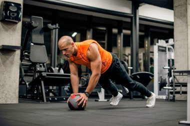 Spor salonundaki adam topla antrenman yapıyor.