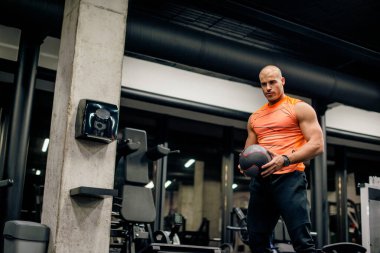 Spor salonundaki adam topla antrenman yapıyor.