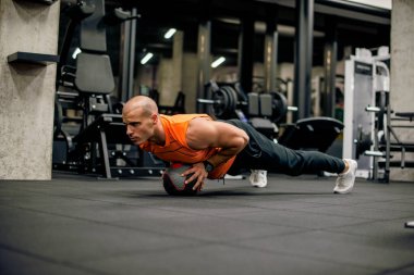 Spor salonundaki adam topla antrenman yapıyor.