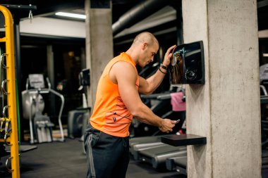 Adam spor salonunda telefonunu kontrol ediyor.