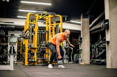 Spor salonundaki adam kettlebell ile salıncak egzersizi yapıyor.