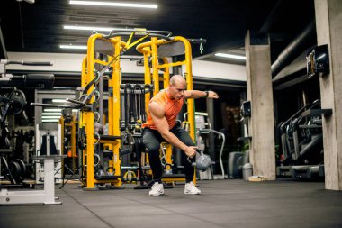 Spor salonundaki adam kettlebell ile salıncak egzersizi yapıyor.