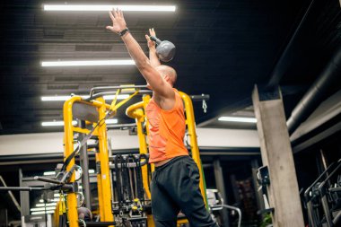 Spor salonundaki adam kettlebell ile salıncak egzersizi yapıyor.