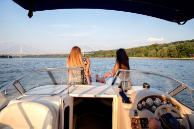 Teknenin ön güvertesinde iki kız içki içiyor.