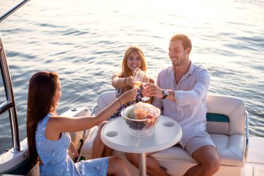 Genç ve çekici insanlar teknede içki içerek iyi vakit geçiriyorlar.