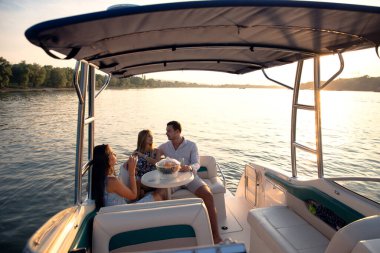 Genç ve çekici insanlar teknede içki içerek iyi vakit geçiriyorlar.