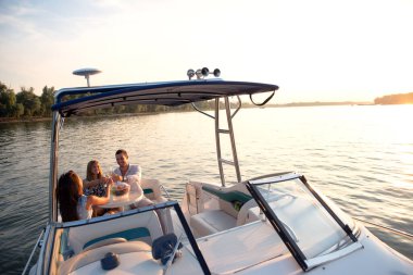 Genç ve çekici insanlar teknede içki içerek iyi vakit geçiriyorlar.