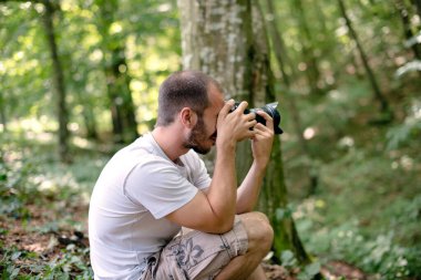Ormanda fotoğraf çeken genç adam.