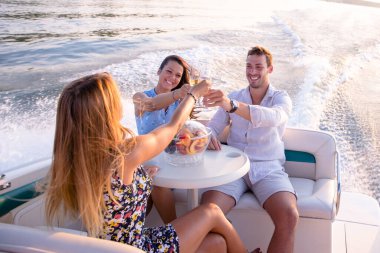 Bir genç adam ve iki güzel kadın şampanya içip teknede eğleniyorlar.