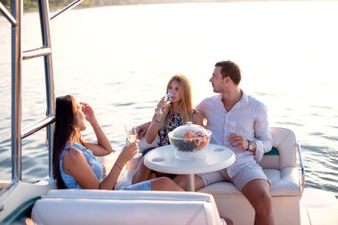 Bir genç adam ve iki güzel kadın şampanya içip teknede eğleniyorlar.