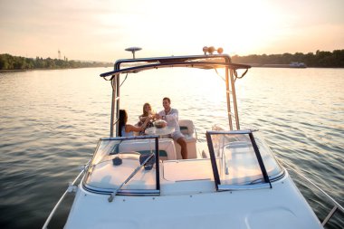 Arkadaşlar teknede eğleniyor, içiyor ve kutluyorlar.