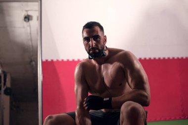 Boksör antrenmandan sonra suyla dinleniyor, yumruğun üzerinde oturuyor.