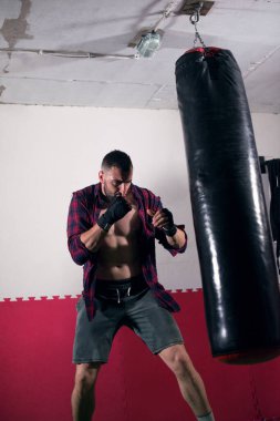 Boks antrenmanında torba yumruklayan bir adam.