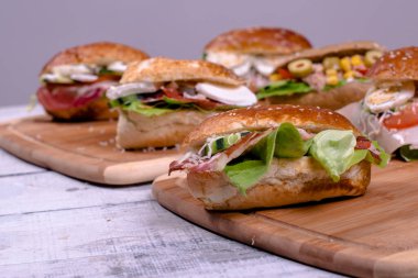 Karışık salata sandviçleri ve ahşap tahtanın üzerinde tamamlayıcı ekmek. Güzel dekore edilmiş.