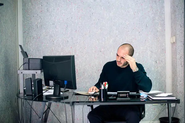 Ofisinde çalışan stresli iş adamı, bilgisayar ekranına bakıyor ve el ele tutuşuyor..