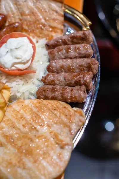 Close up of grilled meat served on plate, chicken and pork meat, cream also.