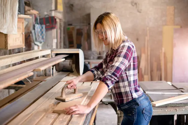 Genç ve çekici sarışın kadın marangoz atölyesinde çalışıyor.