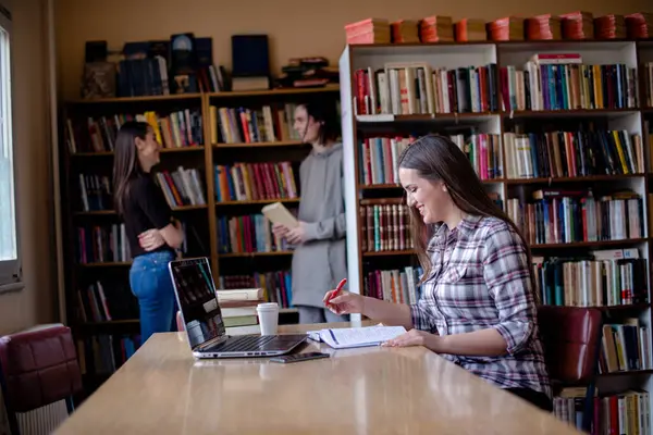 Fröhliche Studentin Macht Ihre Hausaufgaben Der Bibliothek Andere Schüler Reden — Stockfoto