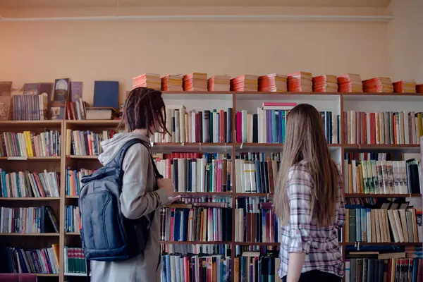 Studenten Stehen Vor Bücherregalen Und Suchen Sich Ein Buch Aus — Stockfoto