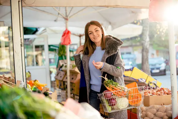 Çiftçi pazarında elinde havuç, soğan, kabak, lahana ve balkabağı olan güzel bir kadının portresi..