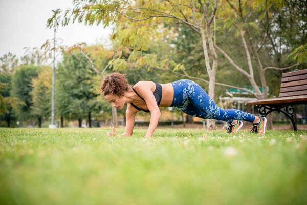 Side view of woman doing push-ups in park.