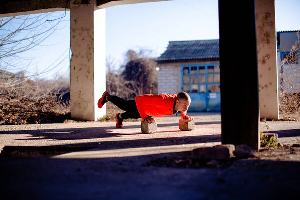 Man doing exercises for legs outdoors, using bricks.