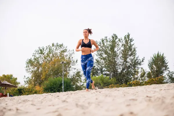 Genç bir kadın güzel bir yaz gününde kumsalda koşuyor..