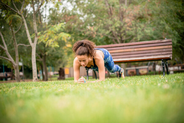 Young woman on strenght training in public park.