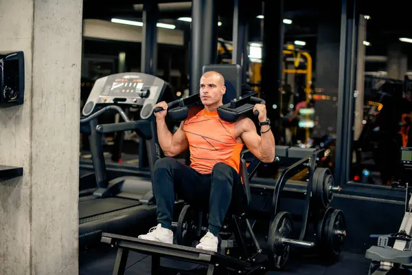 Çekici genç adam spor salonunda egzersiz yapıyor.