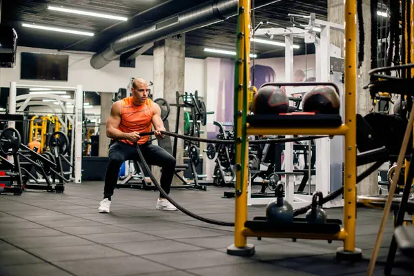 Spor salonunda adam ipi çekiyor, sıkı egzersiz.