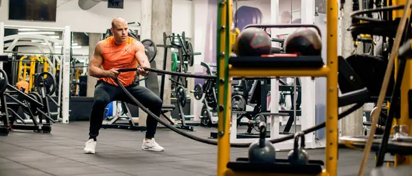 Spor salonunda adam ipi çekiyor, sıkı egzersiz.