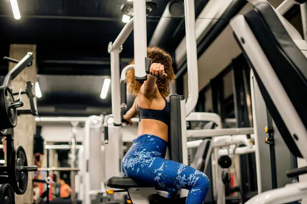 Genç ve çekici bir kadın spor salonunda makineyle çalışıyor.