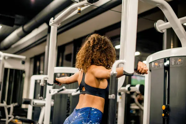 Genç ve çekici bir kadın spor salonunda makineyle çalışıyor.